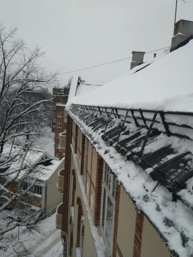 Takkant med snøfangere under tung snølast på bygård